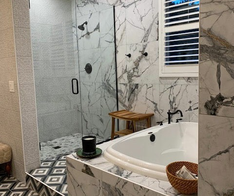 Geo interior design and bathroom remodel project by Tripplehorn Interiors. A luxurious bathroom with tile flooring, marble wall panels, and a walk-in shower.