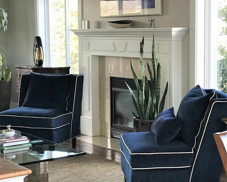Staged sitting area in living room with blue chairs on either side of fireplace